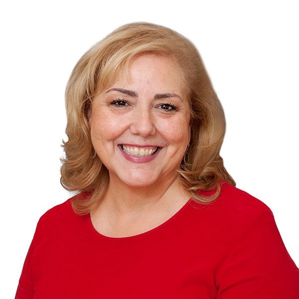 Janet Cribbes in a red top on a white background, smiling