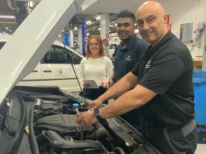 3 people working on a car engine